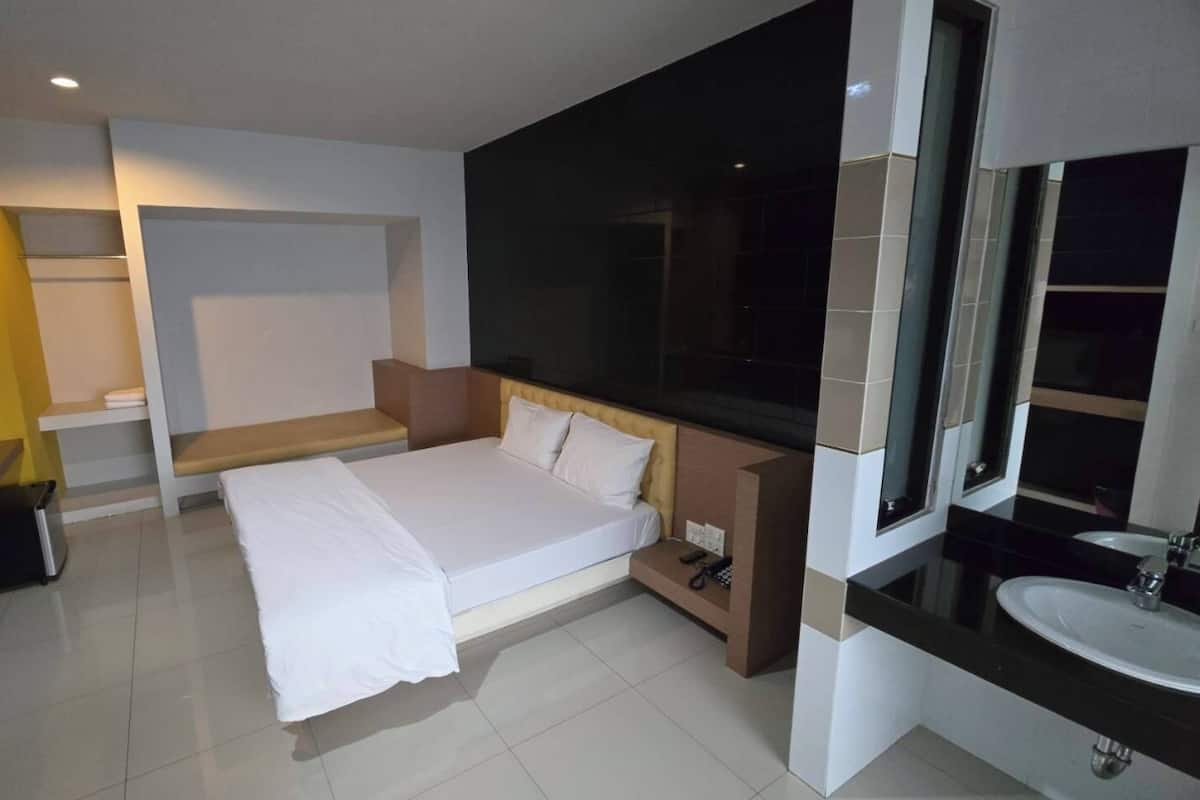 A modern hotel room with a bed, bedside table, and a large mirror.