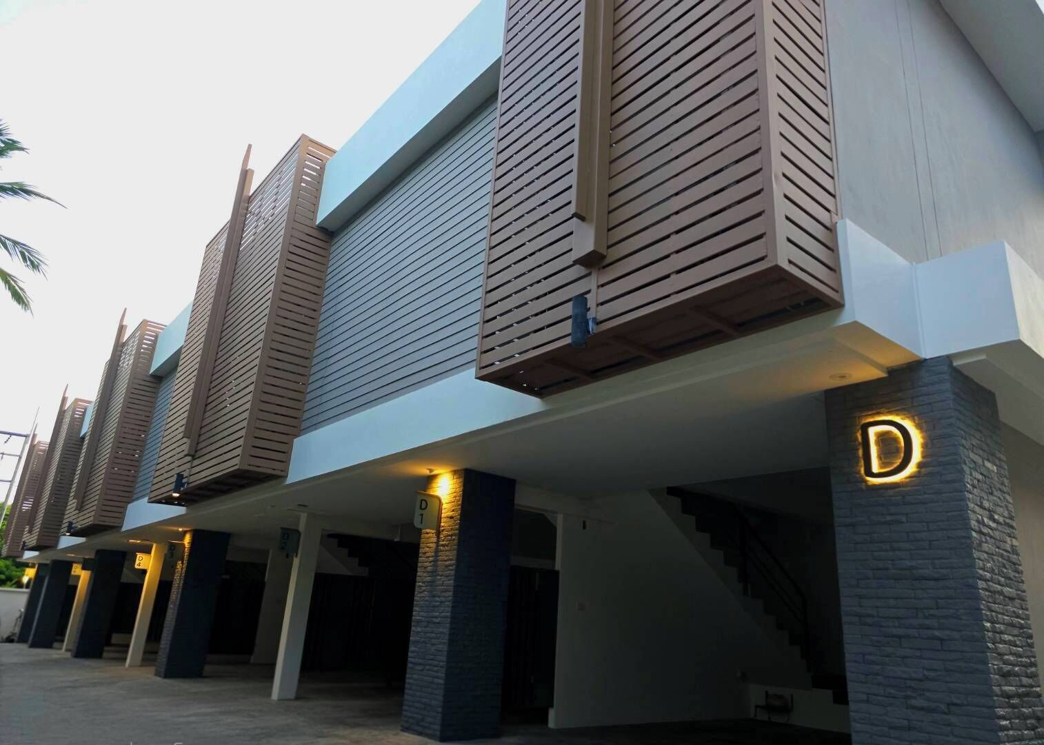 A modern building with a flat roof, large windows, and a prominent 'D' sign on the facade.