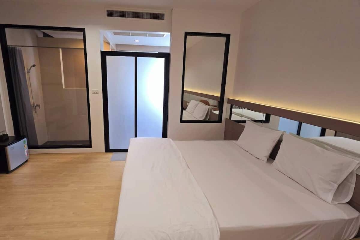 A hotel room with a large bed, a walk-in closet, and a shower area.