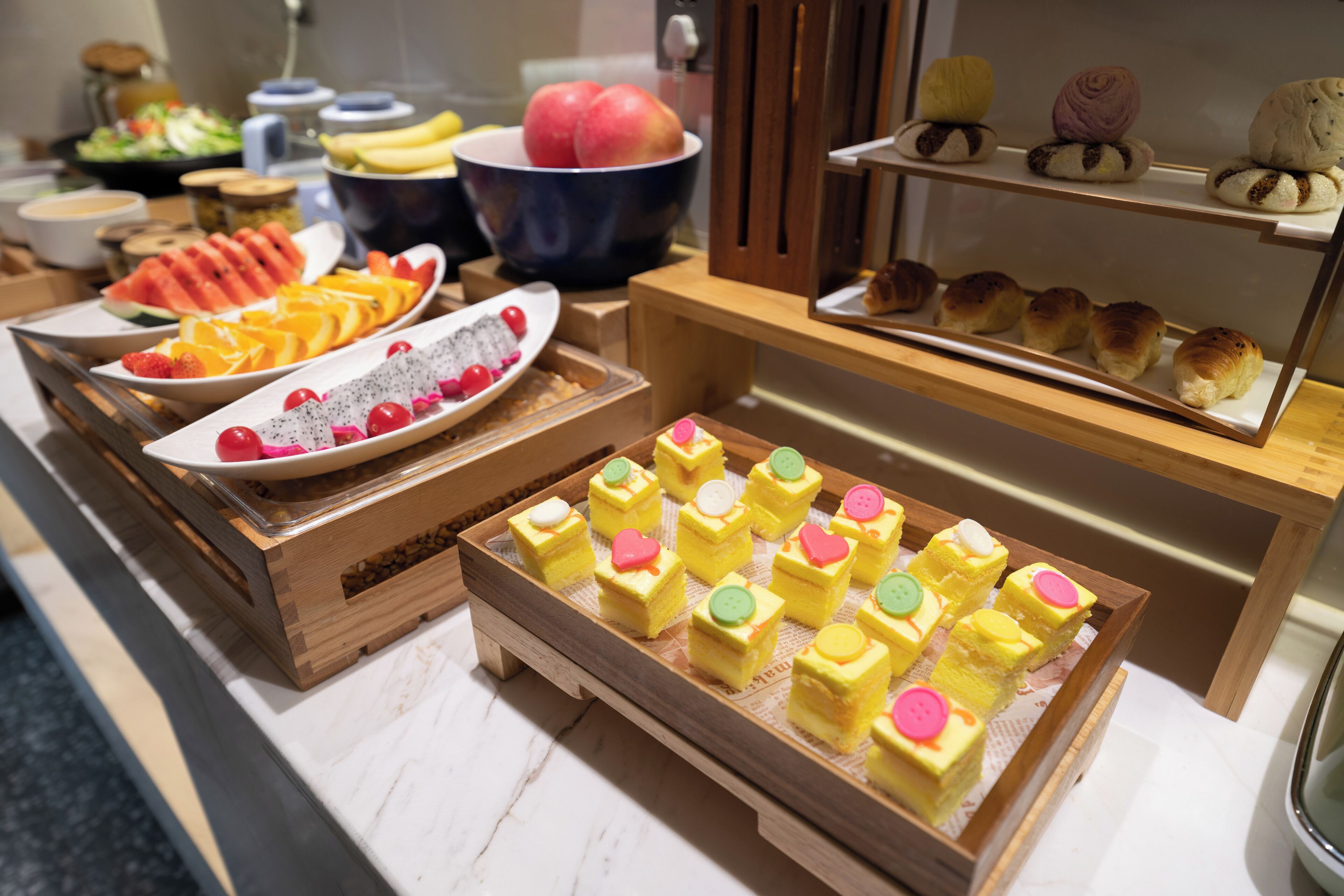 En buffet med et udvalg af mad, herunder frugt, kager og desserter.