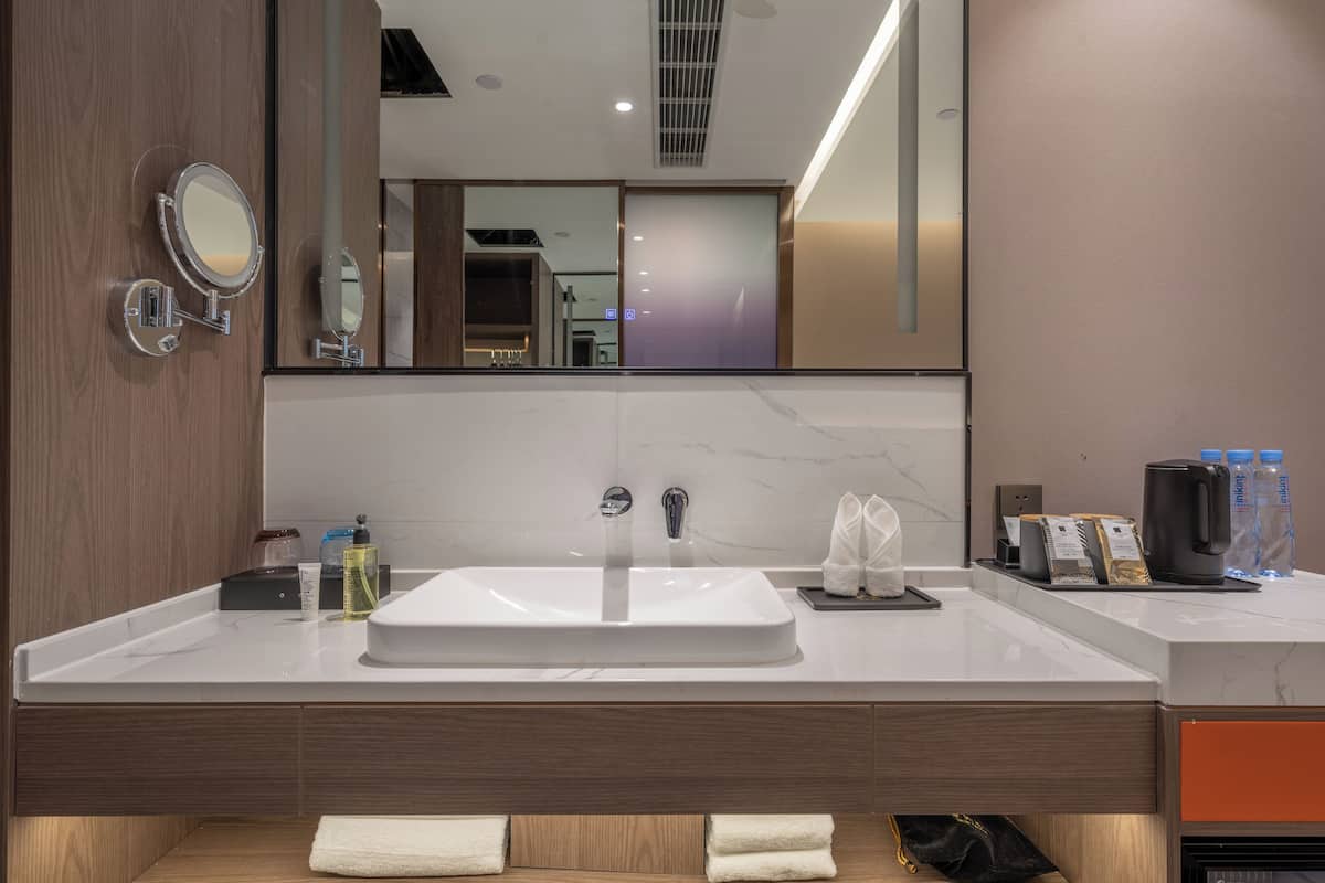A modern bathroom with a large sink, a mirror, and a towel rack.