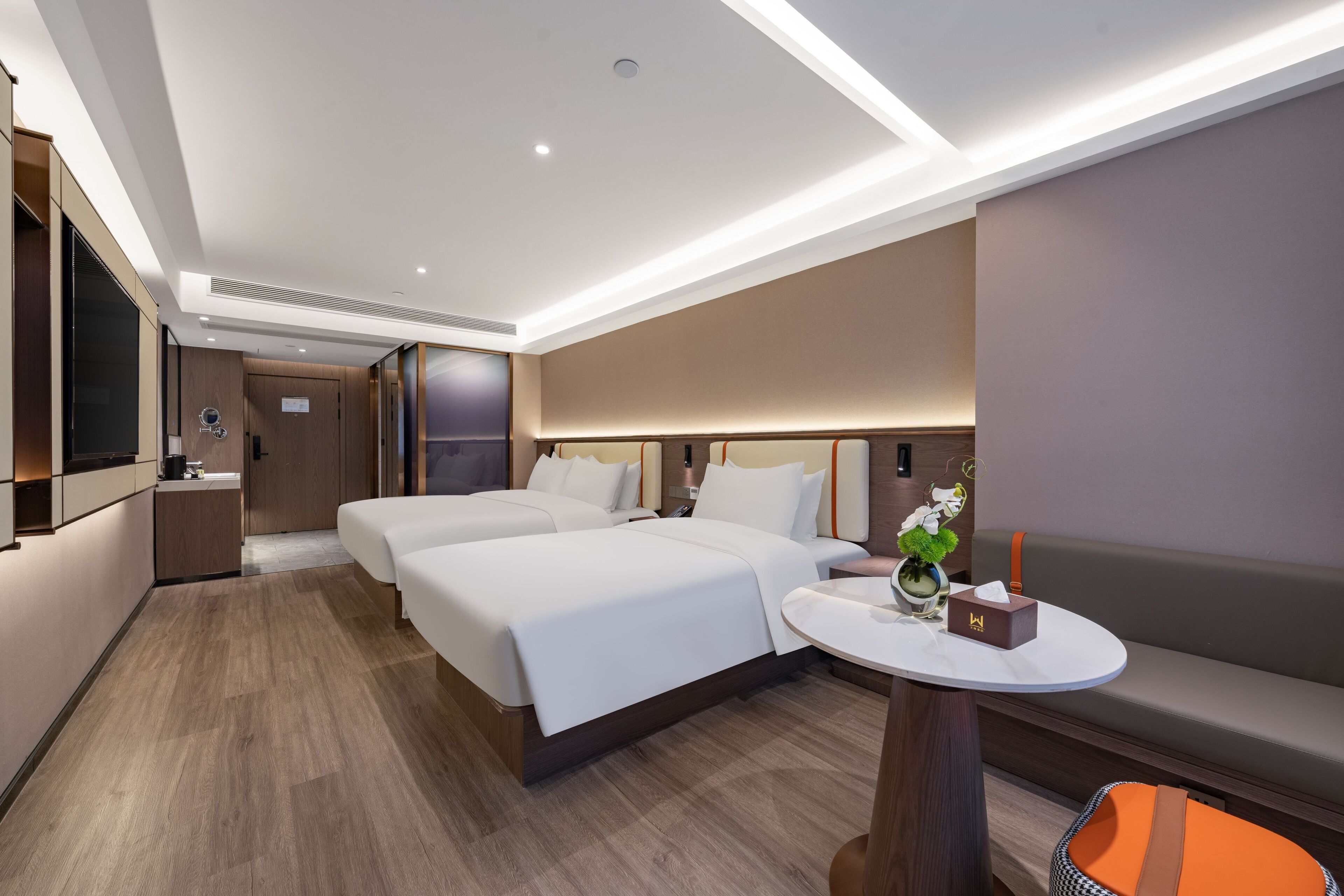 A modern hotel room with a large bed, a desk, and a seating area.
