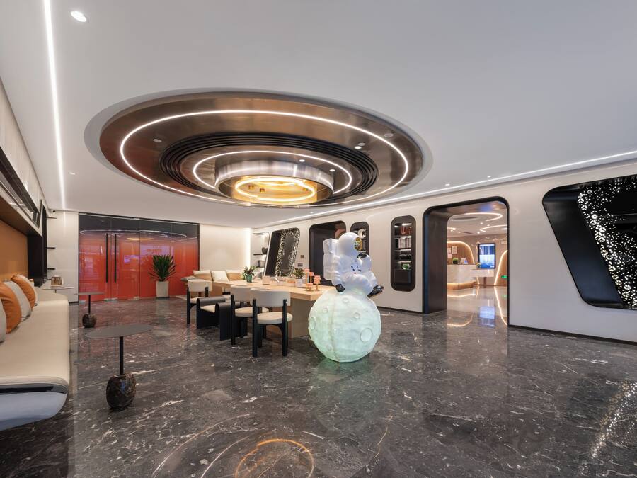 Un vestíbulo moderno con una zona de estar central, un mostrador de recepción y un gran globo decorativo.