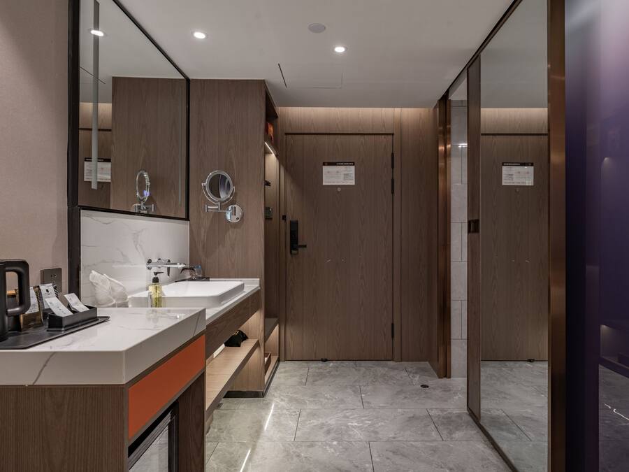 A modern bathroom with two sinks, a mirror, a towel dispenser, and a coffee machine.