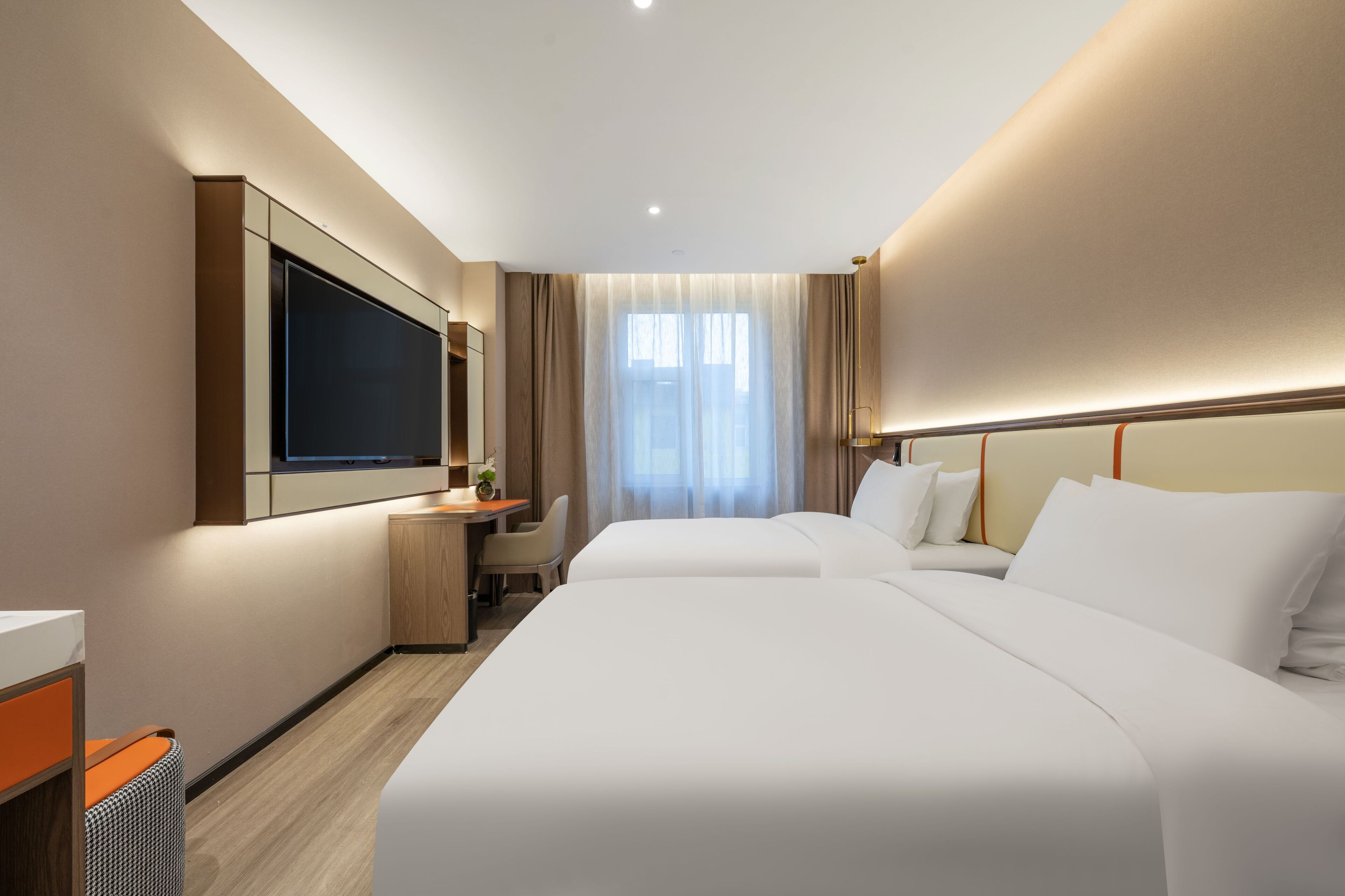 Habitación de hotel con dos camas, un escritorio, televisión y un ventanal con cortinas.