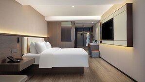 A modern hotel room with a large bed, a bedside table with a phone, a mirror, and a TV mounted on the wall. - WorldHotel Quancheng Sqr Kuanholi Branch (Jinan)