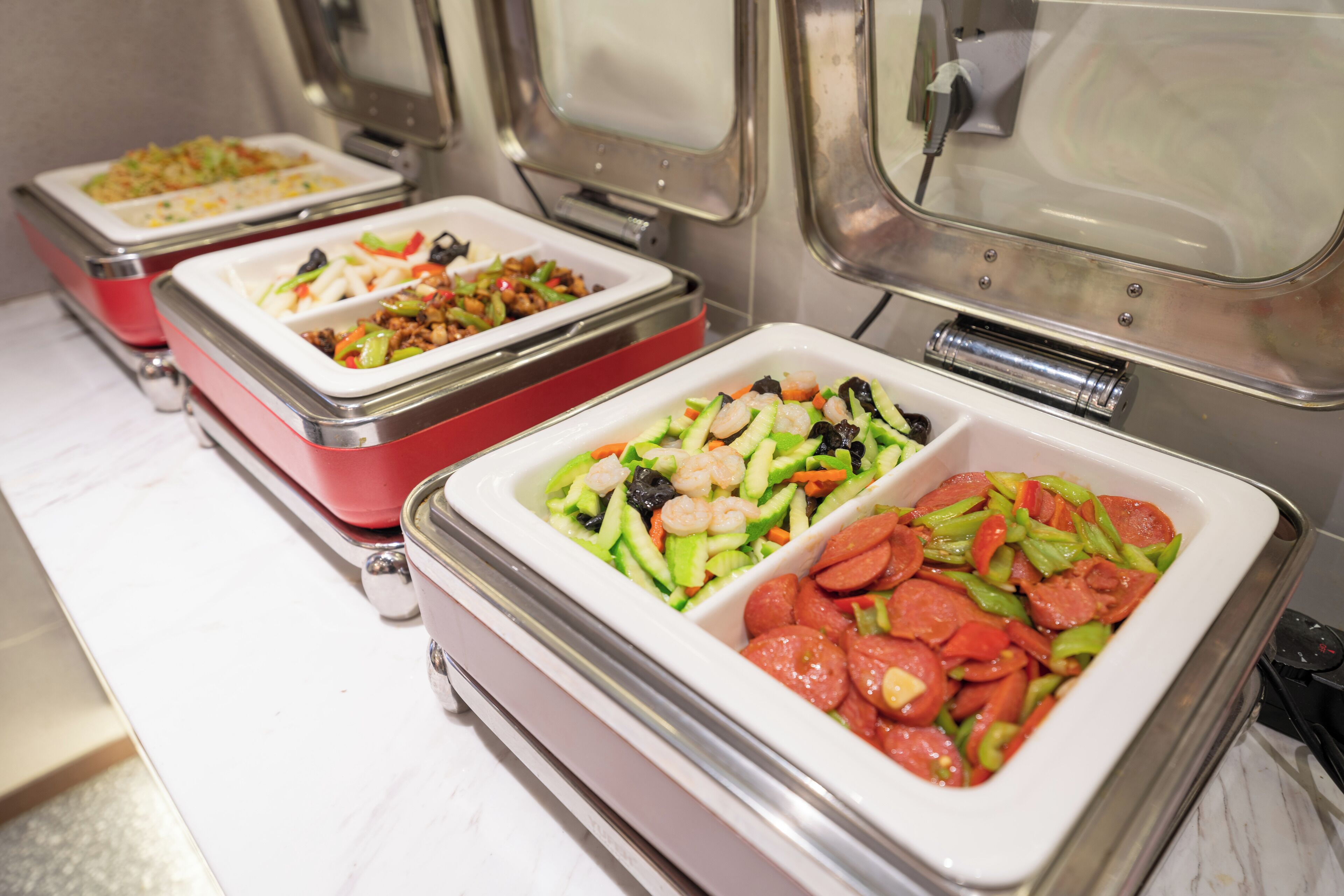 En buffet med forskellige retter, herunder rejer, grøntsager og kød.