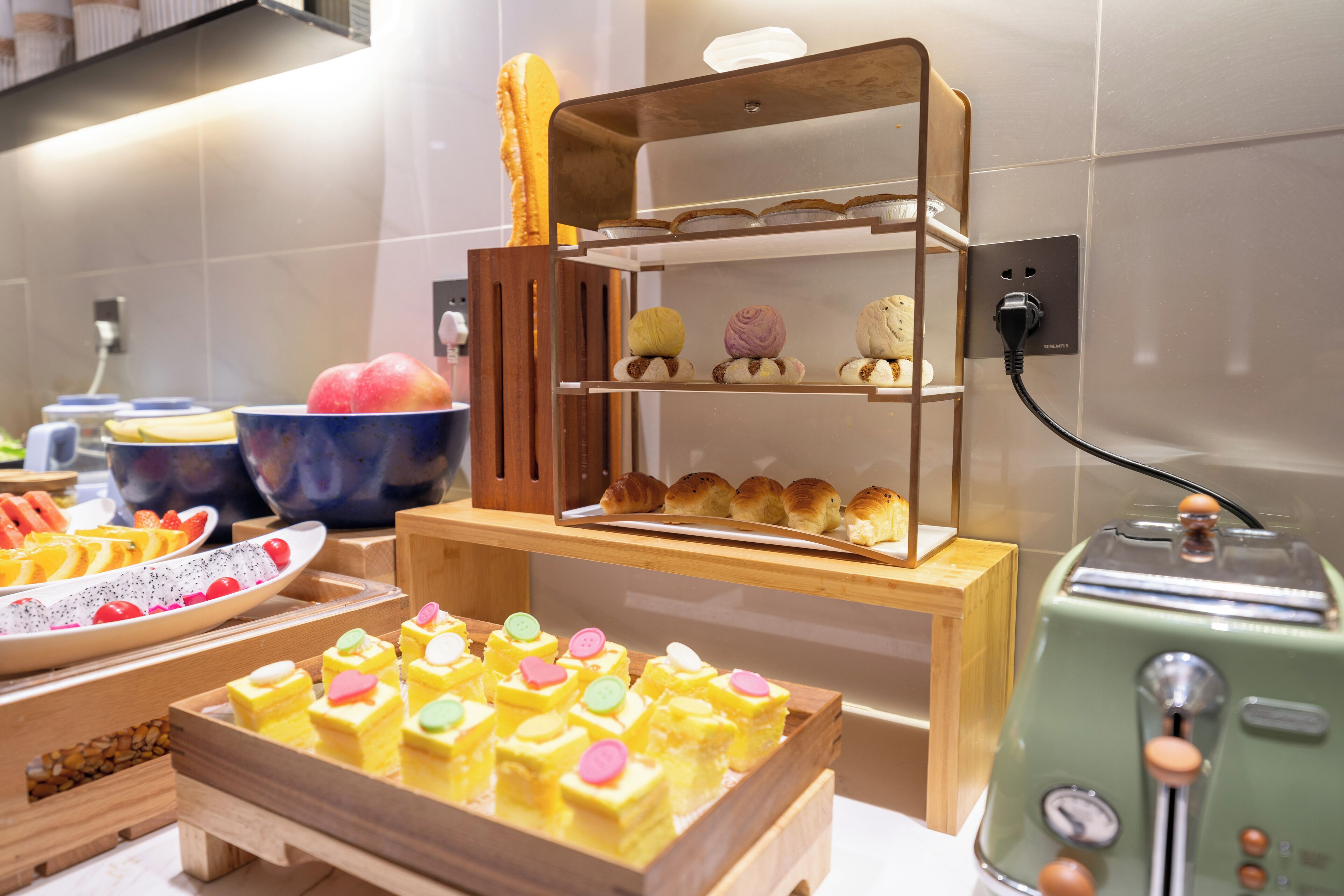 Ein Buffet mit verschiedenen Desserts, Backwaren, einem Toaster und einer Obstschale.