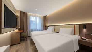 A modern hotel room with two beds, a desk, and a TV.