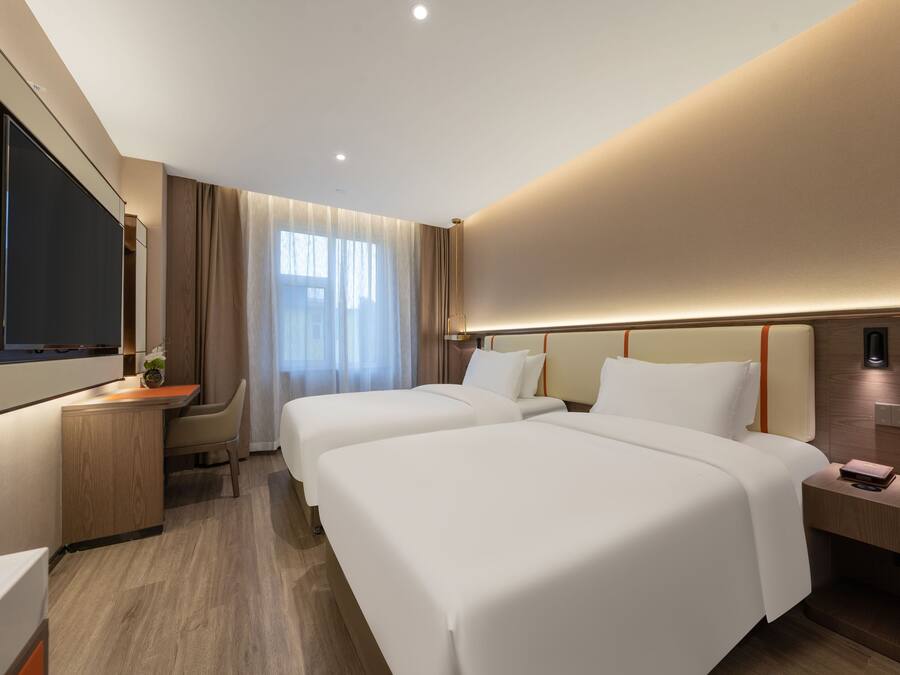 Una habitación de hotel moderna con dos camas, un escritorio y una televisión.