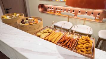 A buffet with various food items and a display of bottles in the background.