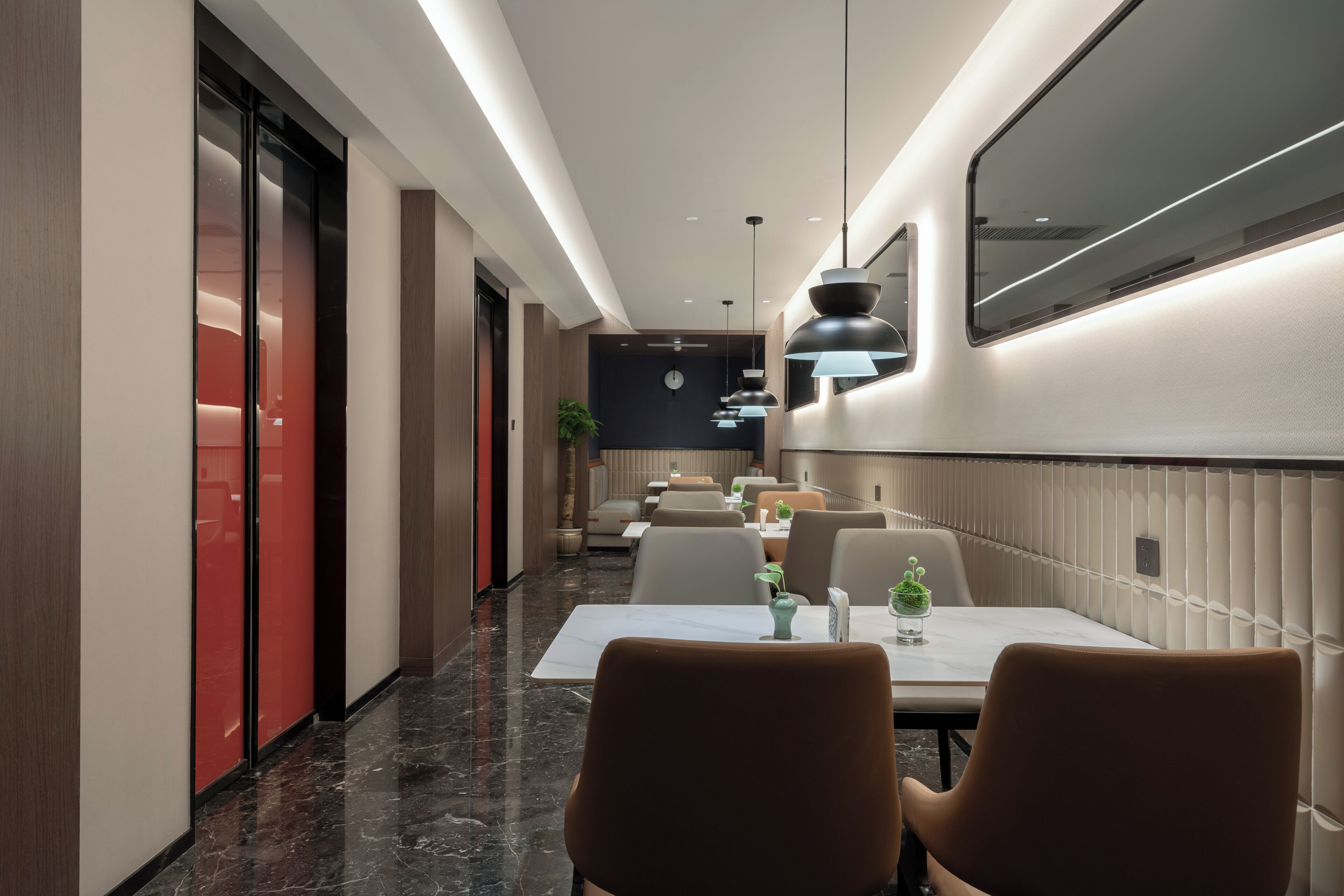 A modern hotel lobby with a long corridor, seating area, and a reception desk.