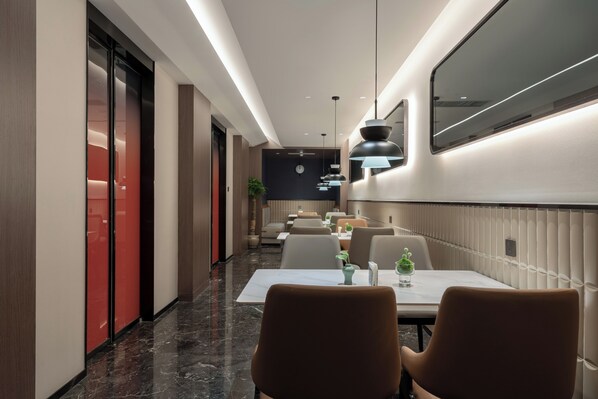 Un moderno vestíbulo de hotel con un largo pasillo, zona de estar y una recepción.