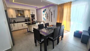 A modern kitchen with white cabinets, a central island, and a dining area with a glass table and black chairs. - Luxurious & Charming 3BR VILLA Palmas Del Mar Pool/Jacuzzi/BBQ in lovely Sosúa (Sosúa)