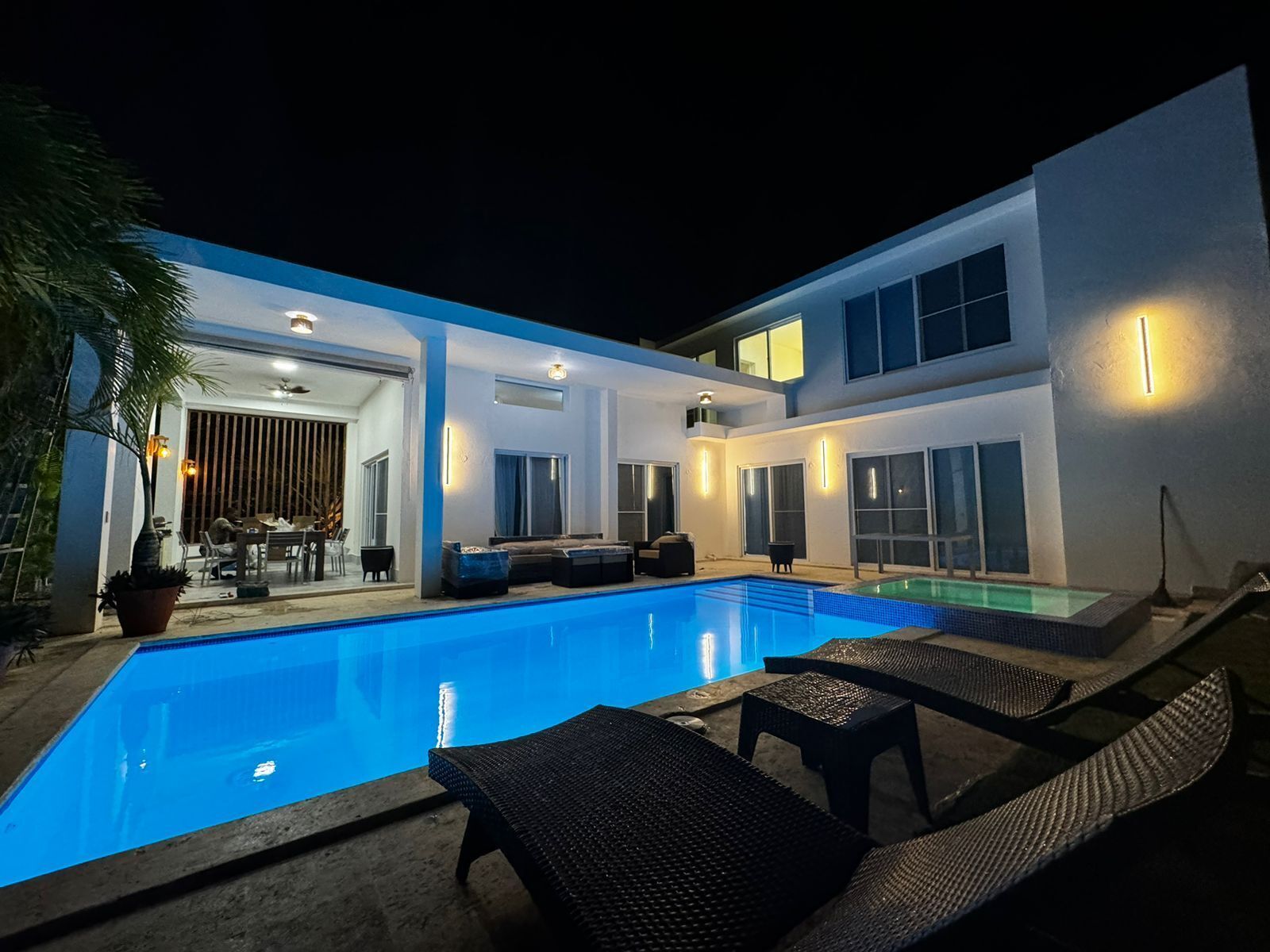 A modern house with a swimming pool, outdoor seating, and a patio area.