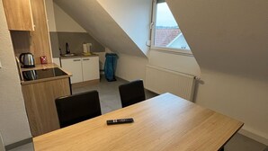 A small, modern kitchen with a dining table and chairs. - nJoy! Business Apartment Pforzheim (Pforzheim)