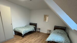 A bedroom with two beds, a ceiling light, and a small table. - nJoy! Business Apartment Pforzheim (Pforzheim)