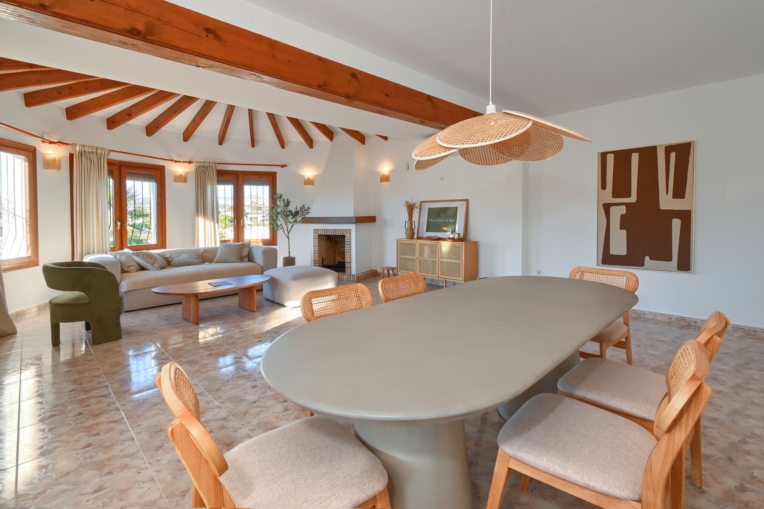 Ein geräumiger Wohnbereich mit einem großen ovalen Tisch, Holzstühlen, einer Couch und einem Kamin.