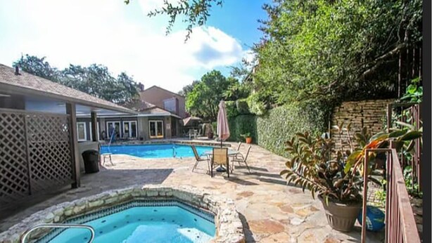 Un patio trasero con piscina, jacuzzi y mobiliario exterior.
