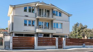 Un immeuble à plusieurs étages doté d’un balcon au deuxième étage, d’une entrée sécurisée et surplombant un ciel dégagé.