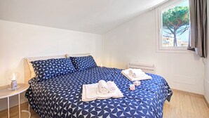 Une chambre à coucher avec un lit, une table de chevet, une lampe et une fenêtre avec des rideaux.