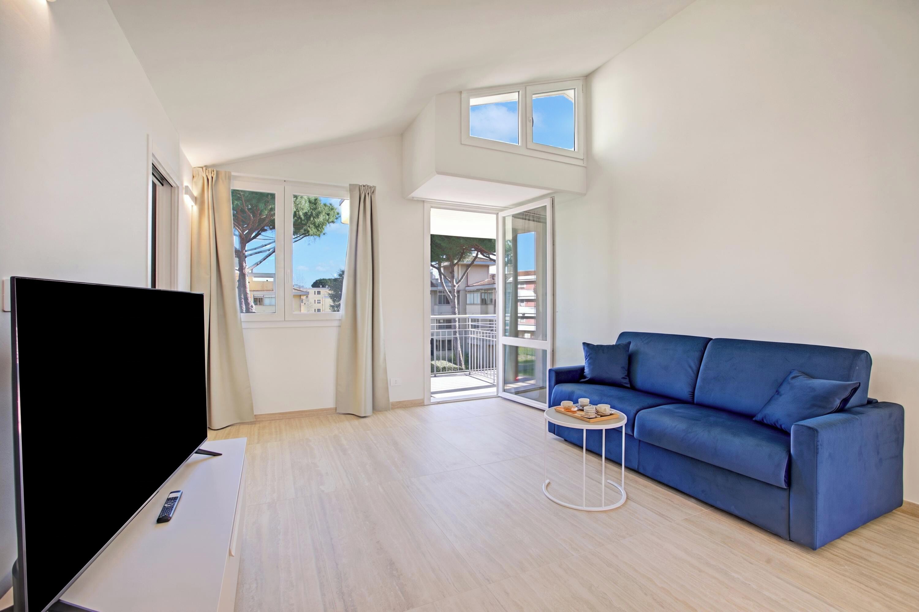 A modern living room with a flat-screen TV, a blue sofa, and a small round table with a tray of items.