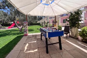A patio area with a foosball table, a vending machine, and a playground with a slide.