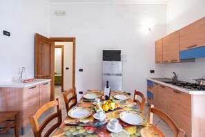 A compact kitchen with a dining table set for four, a refrigerator, and wooden cabinets.