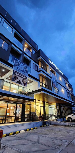 Un immeuble à plusieurs étages, avec une enseigne bien visible indiquant « Gourmet Coffee Lounge », et une entrée clairement identifiable avec un escalier.