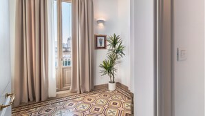 Un couloir avec un revêtement de sol à motifs, une plante en pot et un tableau encadré accroché au mur.