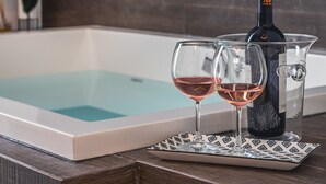 Ett badkar med två glas vin och en flaska på ett brickbord.