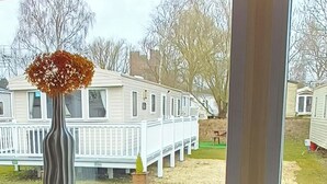 Une rangée de maisons mobiles aux façades blanches, délimitée par une clôture blanche.