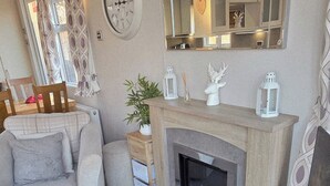 Un salon chaleureux avec une cheminée, une horloge et des objets décoratifs disposés sur la cheminée.