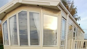 Une maison mobile dotée de grandes fenêtres, d’un porche abrité et d’un garage.
