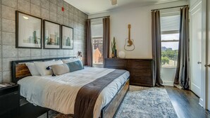 A modern bedroom with a large bed, a ceiling fan, a dresser, and a window with curtains. - Urban King Loft - Cali King - 8 Min to Broadway! (Nashville)