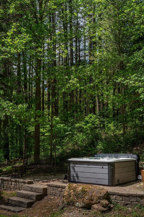 A hot tub in a forested area with stone steps leading up to it.