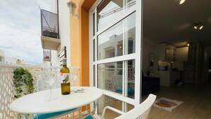A balcony with a table and chairs, a bottle of wine, and a glass.