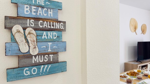 A wall decoration with a beach-themed message and flip-flops.