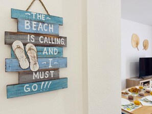 A wall decoration with a beach-themed message and flip-flops.