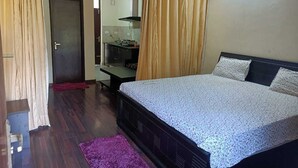 Ein Schlafzimmer mit einem Bett, einem Schreibtisch und einem Stuhl. Eine Tür und ein Vorhang sind vorhanden.