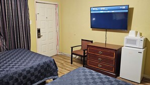 A hotel room with two beds, a television, a desk with a microwave, and a chair. - Deluxe Inn (Stuttgart)