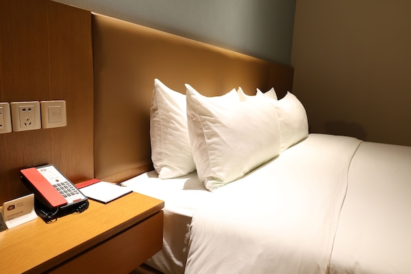 A hotel room with a wooden nightstand, a red telephone, a notepad, and white bedding. - Artels Collection Lingang Shanghai (Shanghai)