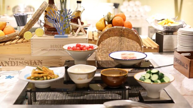 Une table de buffet proposant une variété d’aliments, notamment des fruits, des légumes et des plats servis dans des bols.