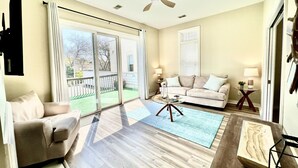 A spacious living room with a large sliding glass door leading to a backyard, a ceiling fan, and a beige sofa. - Downtown, Roof Deck, Fireplace (Saugatuck)