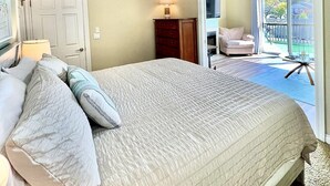 A bedroom with a large bed, a ceiling fan, a nightstand, a lamp, and a view of an outdoor patio. - Downtown, Roof Deck, Fireplace (Saugatuck)