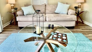 A living room with a glass coffee table, beige sofa, and two side tables with lamps. - Downtown, Roof Deck, Fireplace (Saugatuck)
