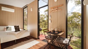 A modern bedroom with a bed, bedside table, and a view of the outdoors. - Maroota Greens JOY by Tiny Away (Maroota)
