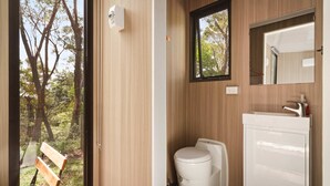 A bathroom with a toilet, sink, and a window with a view of trees. - Maroota Greens JOY by Tiny Away (Maroota)