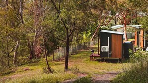 A secluded cabin with a small deck and a fan, surrounded by dense forest. - Maroota Greens JOY by Tiny Away (Maroota)