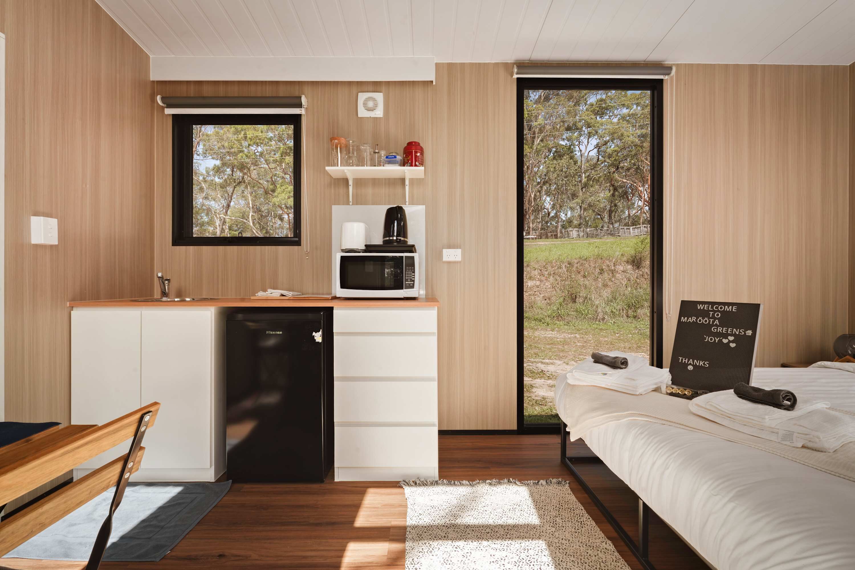 Une chambre moderne avec une cuisine intégrée, une grande fenêtre et un panneau d’accueil.